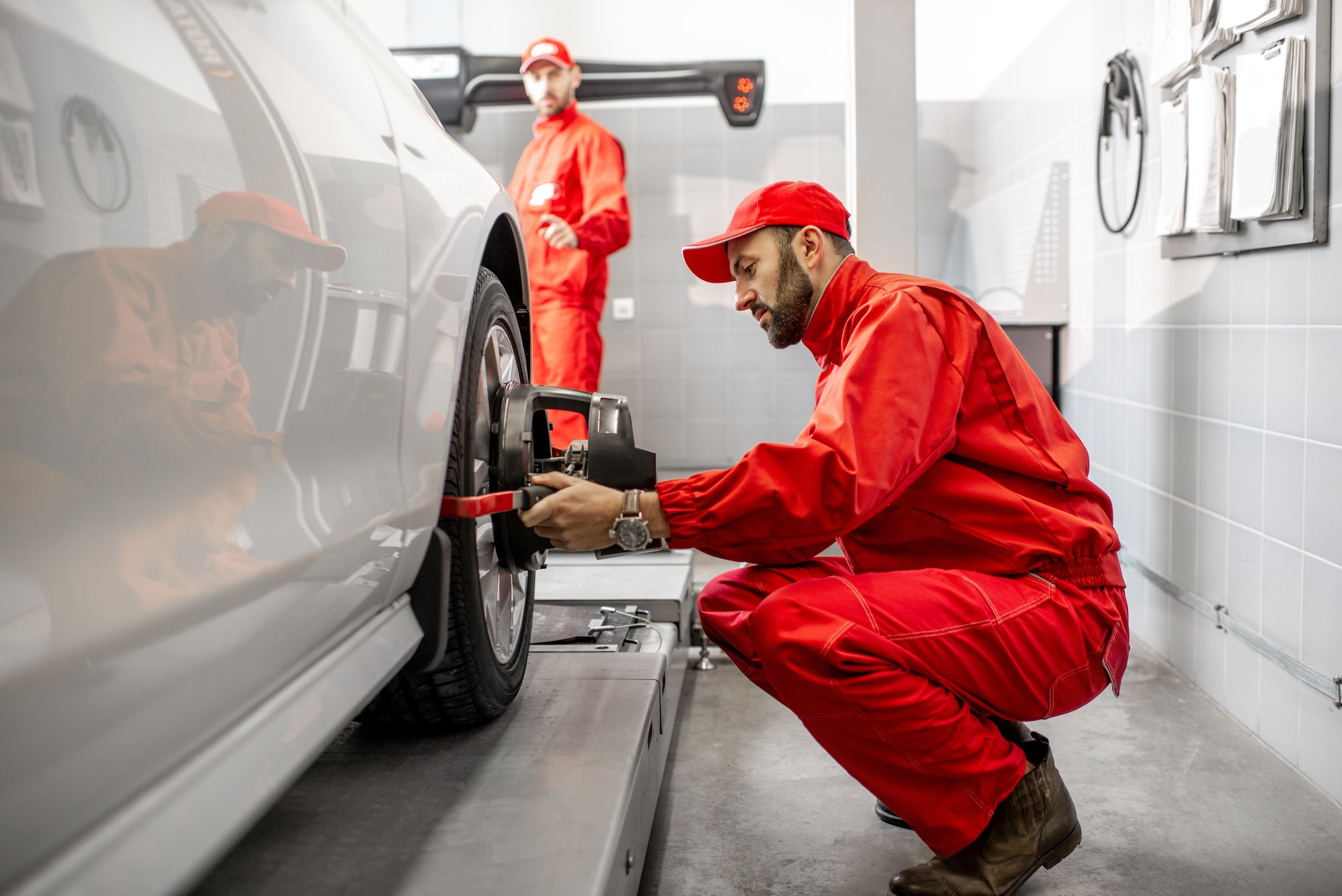 Auto mechanics making wheel alignment at the car service