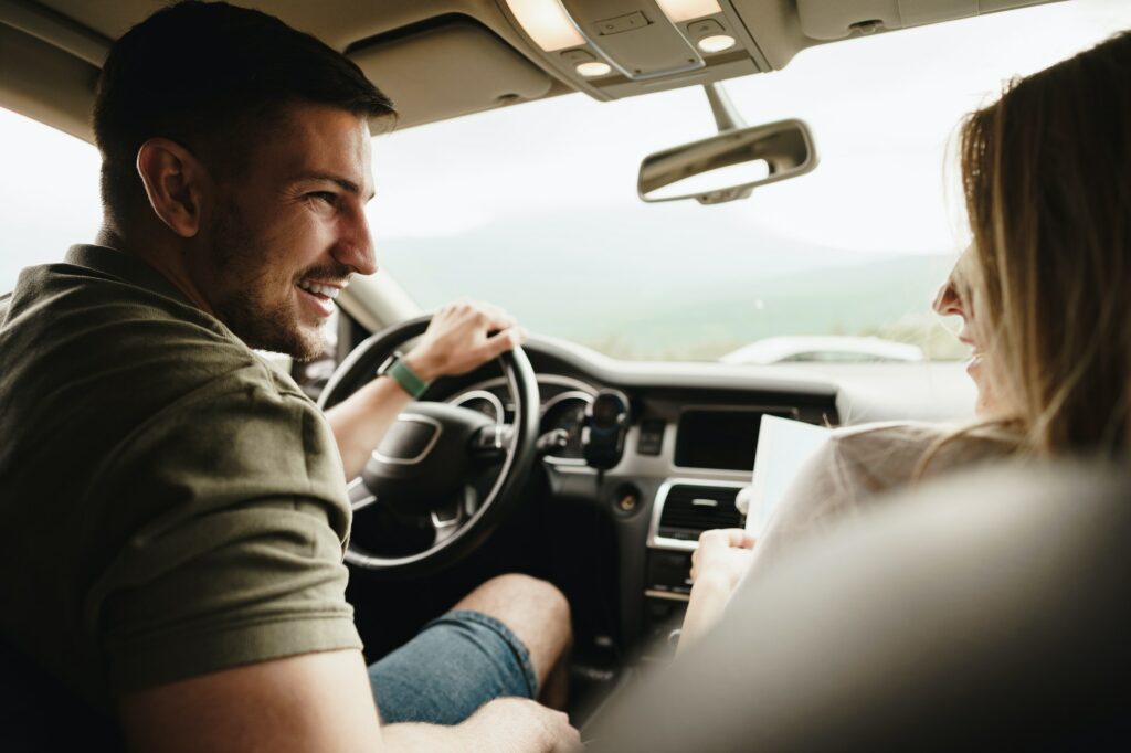 Beautiful young couple sitting on front passenger seats and driving a car