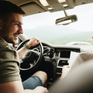 Beautiful young couple sitting on front passenger seats and driving a car
