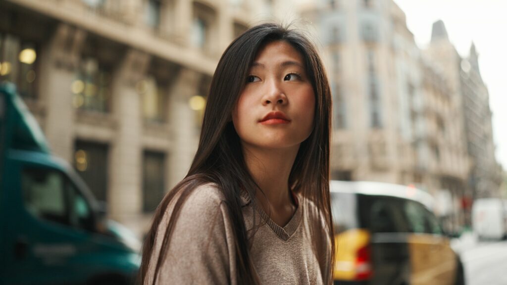 eautiful Asian woman standing on the street with passing cars on background