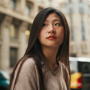 eautiful Asian woman standing on the street with passing cars on background